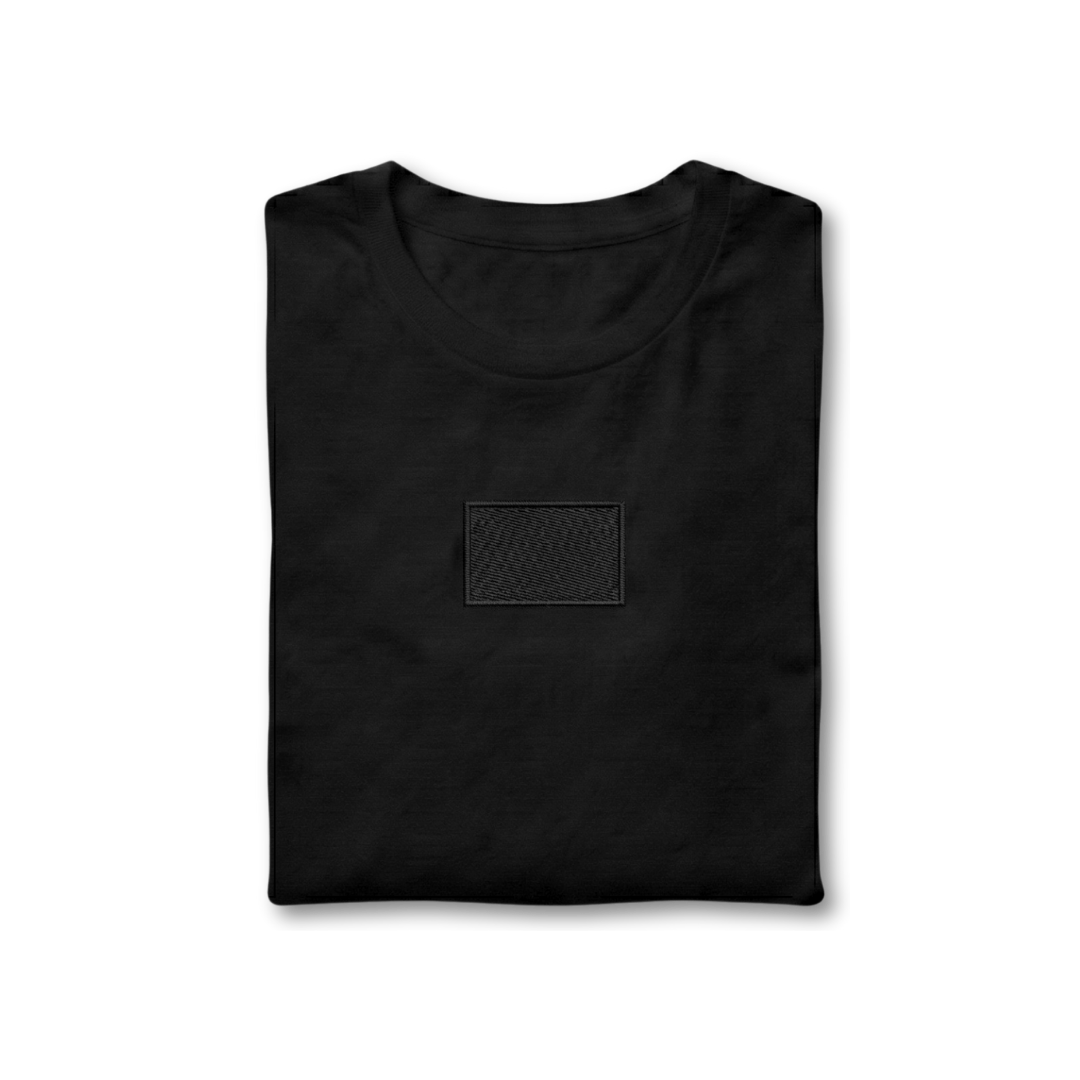 Folded black t-shirt with a small rectangular patch on a white background